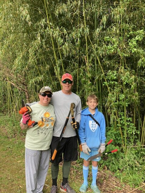 A man and two women holding guns next to a tree.